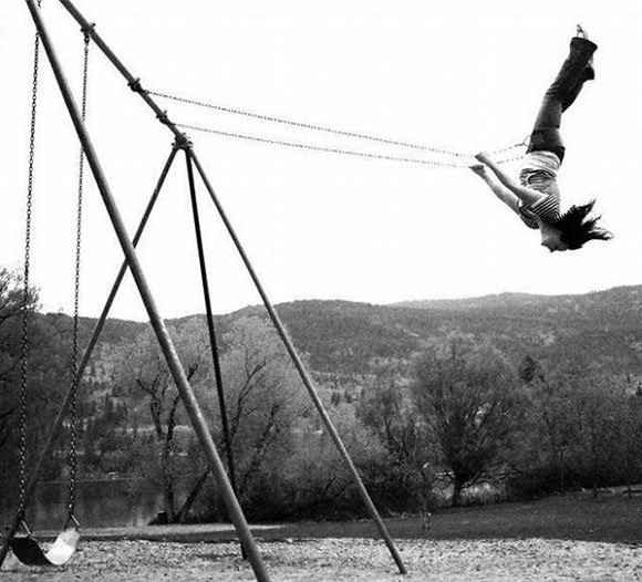 A little girl, upside down on a swing.